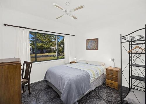 a bedroom with a bed and a window at Ronnie s Cottage in Mylestom