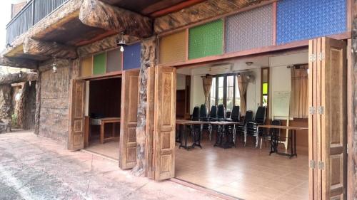 a building with wooden doors and tables and chairs at Soft Resort Kad Farang Hangdong in Ban Yang Plao