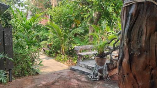 a bench in a garden with a potted plant at Soft Resort Kad Farang Hangdong in Ban Yang Plao