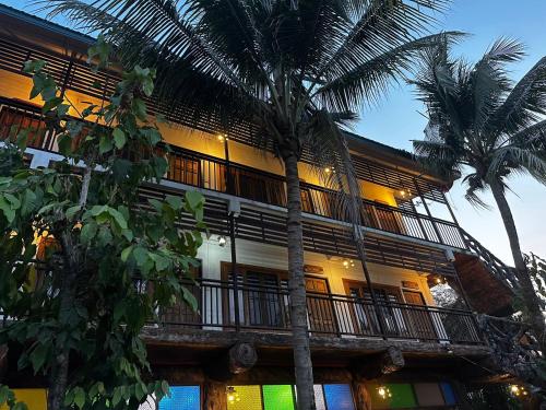 a building with palm trees in front of it at Soft Resort Kad Farang Hangdong in Ban Yang Plao