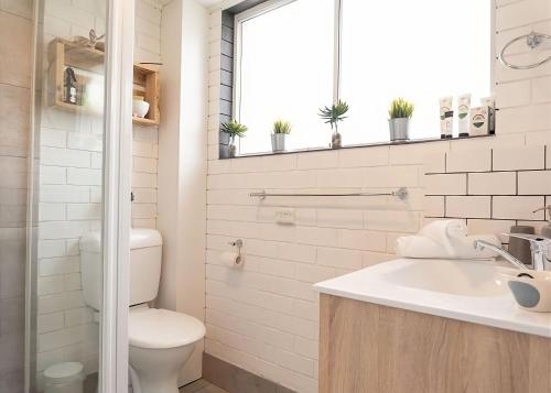 a bathroom with a toilet and a sink and a window at Lemongrass in Sawtell