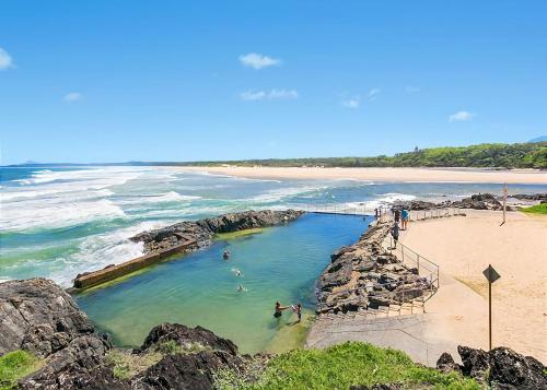 a group of people swimming in a pool on a beach at Lemongrass in Sawtell