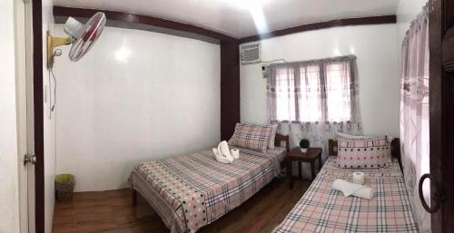 a bedroom with two twin beds and a window at Alexandra's Transient Haus in Donsol