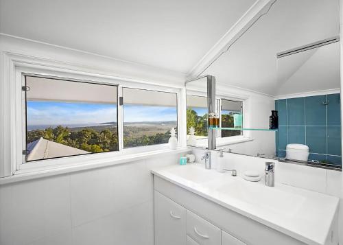 a white bathroom with a large window and a sink at Sea Breeze in Coffs Harbour