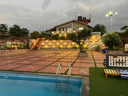 a swimming pool with a house in the background at Hilltop Resort and Glamping Wai, Near Panchgani in Wai