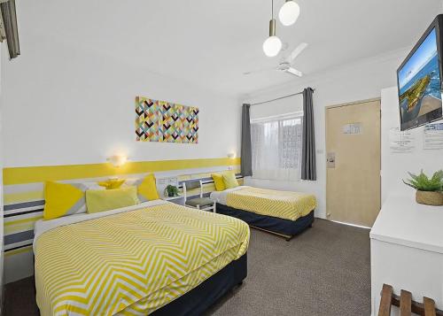 una camera d'albergo con due letti e una scrivania di Coasters 30 a Sawtell