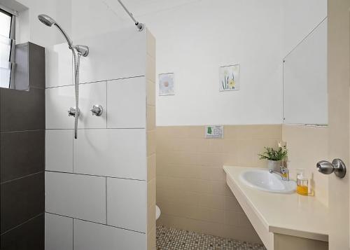 ein weißes Bad mit einem Waschbecken und einer Dusche in der Unterkunft Coasters 30 in Sawtell