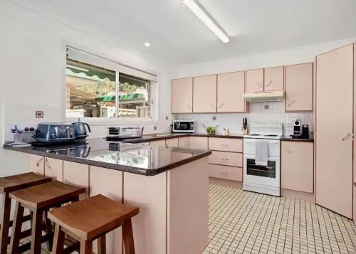 a kitchen with white cabinets and white appliances at Geoff and Mary s in Urunga