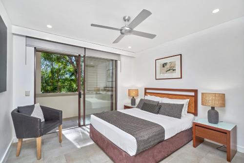 a bedroom with a bed and a chair and a window at Temple 313 Spacious Modern 3 Bedroom Apartment Balinese Style Resort in Palm Cove