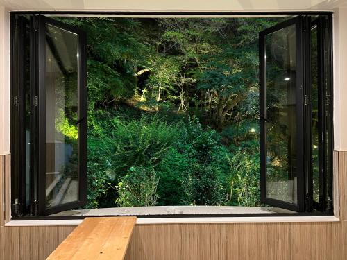 a window with a wooden table in front of a forest at Denbasta forest Hotel in Busan