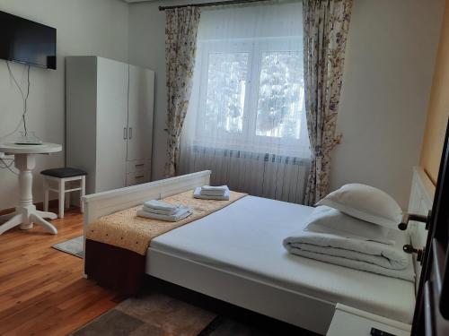 Un dormitorio con una cama y una ventana y una mesa. en Pensiunea Putnisoara, en Putna