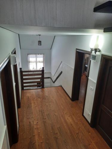 Una habitación vacía con suelo de madera y escaleras. en Pensiunea Putnisoara, en Putna