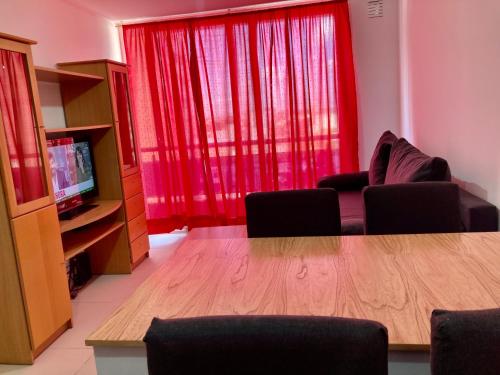 a living room with a table and a red curtain at 6-Maravilloso departamento morón centro in Morón