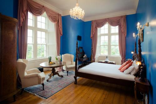 Kinnitty Castle Hotel في Kinnitty: غرفة نوم زرقاء مع سرير وطاولة وكراسي