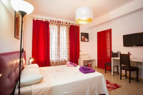 a bedroom with a bed with red curtains and a desk at Colapesce in Santa Teresa di Riva