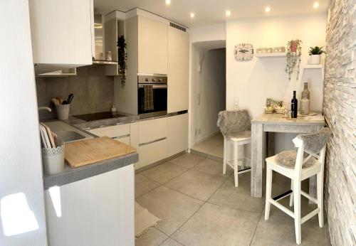 cocina con armarios blancos, mesa y sillas en Residenza Tulipani, en Losone