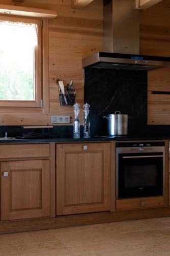 a kitchen with wooden cabinets and a stove top oven at Hôtel Les Roches Fleuries in Cordon