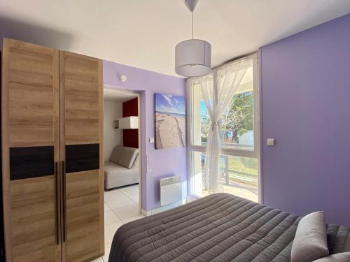 une chambre avec des murs violets et un lit et une fenêtre dans l'établissement Appartement 2 pers. rénové avec balcon, accès plage et centre-ville à pied - Classé 2* - FR-1-231-285, à Bretignolles-sur-Mer
