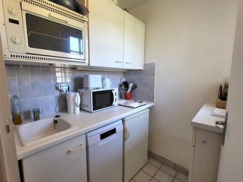 une petite cuisine avec un évier et un micro-ondes dans l'établissement Charmant Duplex Près de la Plage à Cabourg - Balcon Sud, 4 pers., Tout équipé - FR-1-465-93, à Cabourg