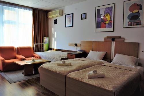 a hotel room with two beds and a chair at Стаи за гости При Зори и Ицо in Nova Zagora