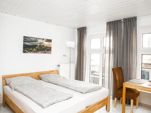 ein Schlafzimmer mit einem Bett, einem Schreibtisch und einem Fenster in der Unterkunft Ferienwohnungen Merl in Zell an der Mosel
