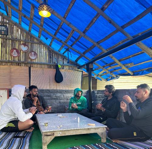 een groep mensen die rond een tafel zitten bij Dreamwoods A travellers farmhouse in Dharamshala