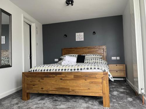 a bedroom with a wooden bed and a gray wall at St Georges Guest House in St Peter Port