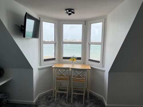 a small table in a room with three windows at St Georges in St Peter Port