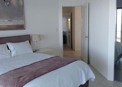 a bedroom with a white bed and a sliding glass door at Belvedere in Kororo Basin
