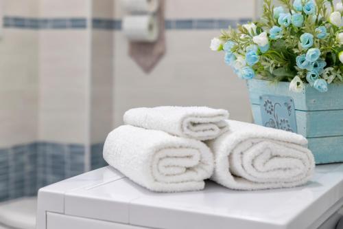 a pile of towels on a bathroom counter with a vase of flowers at Casa Vacanze San Michele in Alghero