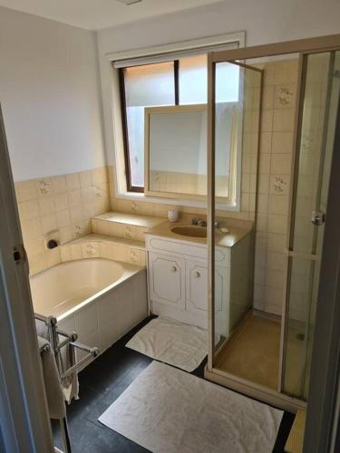 a bathroom with a tub and a sink and a mirror at Ocean Grove - walk to Beach, Park, Cafe & Pub in Ocean Grove