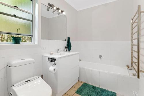 y baño blanco con aseo, lavabo y bañera. en 1 38 Boronia St, en Sawtell
