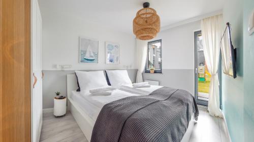 a white bed in a room with a window at Sun & Snow prywatne apartamenty w obiekcie Nautikka Resort in Krynica Morska