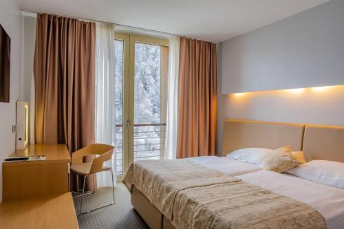a hotel room with a bed and a desk and a window at Hotel Thermana Park Laško**** Superior in Laško
