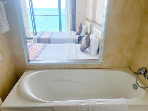 a bathroom with two beds and a tub with a mirror at Lenid Ocean View Hotel in Nha Trang