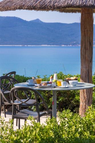 een tafel met eten erop met uitzicht op de oceaan bij Hotel Le Ruesco in Olmeto