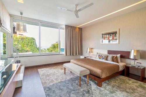 a hotel room with a bed and a large window at Stars By The Bay & BBQ Grill by StayVista in Dabolim