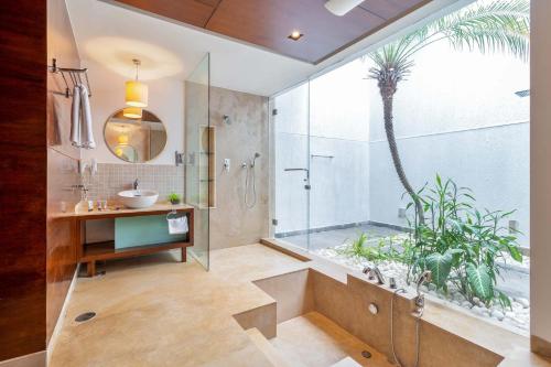 a bathroom with a shower and a palm tree at Stars By The Bay & BBQ Grill by StayVista in Dabolim