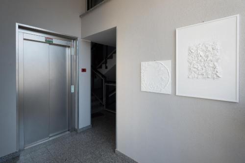 een hal met twee schilderijen aan een muur en een deur bij Bed&Business Nick Bellezza-San Siro Stadio-Rho Fiera in Settimo Milanese