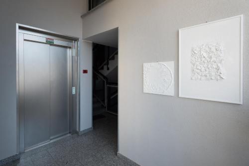 a hallway with two paintings on a wall and a door at Bed&Business Nick Bellezza-San Siro Stadio-Rho Fiera in Settimo Milanese