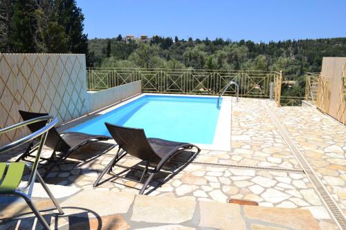 a swimming pool with two chairs and a table at Agios Nikitas View in Agios Nikitas