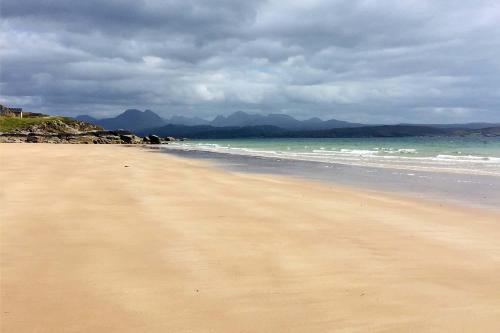 a sandy beach with the ocean on a cloudy day at Asgard in Big Sand