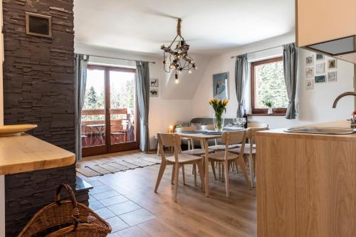 - une cuisine et une salle à manger avec une table et des chaises dans l'établissement udanypobyt Apartamenty Słoneczne, à Kościelisko