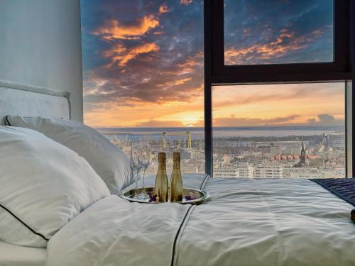 two bottles of champagne on a bed in front of a window at Apartament White Sky 20 Hanza Tower- Free parking in Szczecin