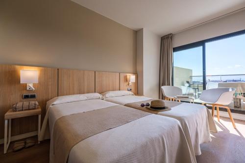 a hotel room with a large bed and a large window at Hotel California Garden in Salou