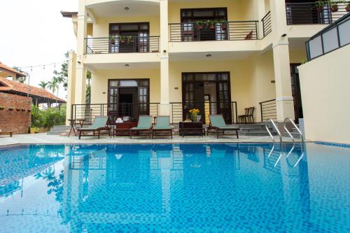 a villa with a swimming pool in front of a building at Windbell Villa Hoi An in Hoi An
