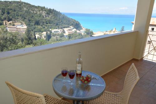 a table with two glasses of wine on a balcony at Agios Nikitas View in Agios Nikitas