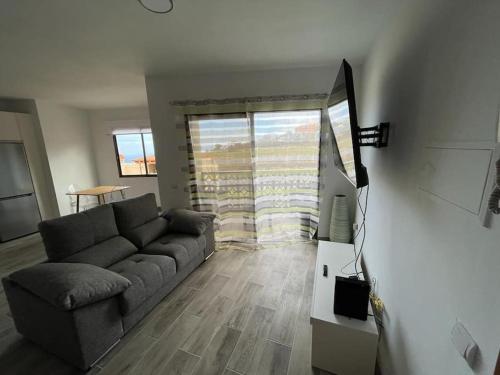 een woonkamer met een bank en een flatscreen-tv bij New 2023 full equipped stylish digi in Los Realejos