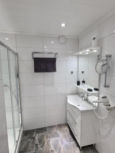 uma casa de banho branca com um chuveiro e um lavatório. em Ferienwohnung Akay em Langenlonsheim