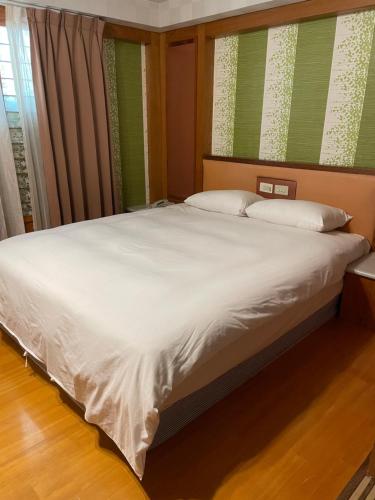 a bed with white sheets and pillows in a bedroom at Mei Hua Hotel in Kaohsiung